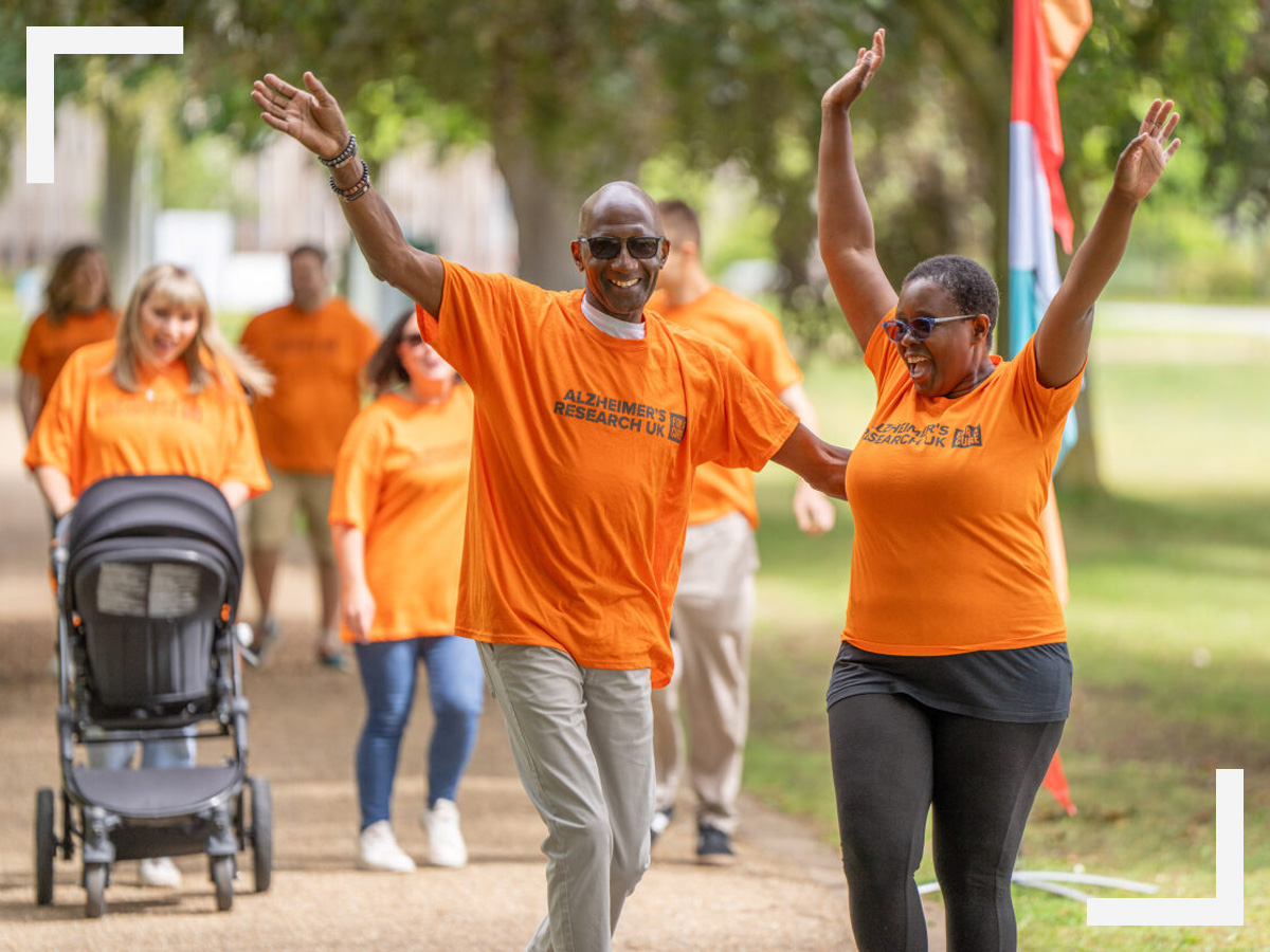 Two people in Alzheimers Research UK orange tshirt dancing along the Walk For A Cure route